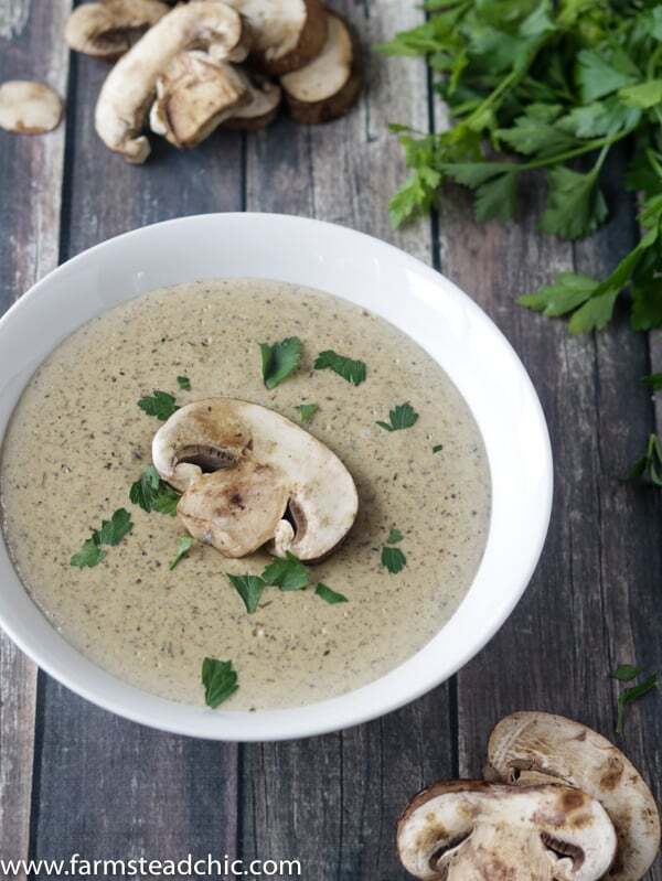 Keto Cream of Mushroom Soup in a white bowl on a dark barn wood background with fresh mushrooms and parsley.